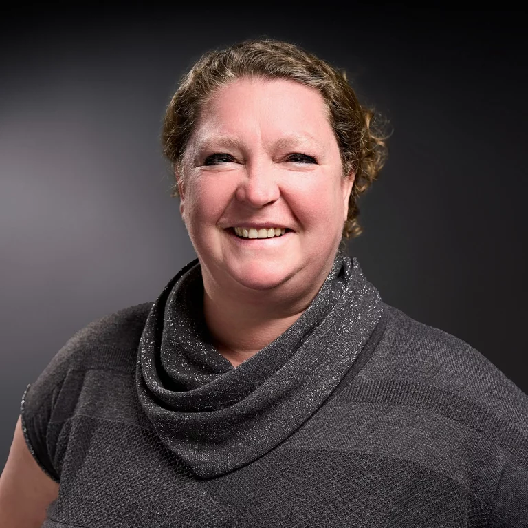 Portrait-Foto von Nadine Welscher, Projektleitung, in einem grauen Pullover. Sie lacht.